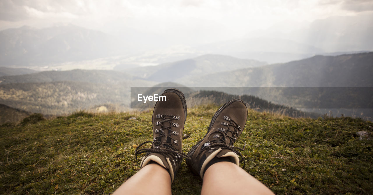 shoe, personal perspective, human leg, mountain, one person, low section, nature, leisure activity, footwear, limb, human limb, mountain range, environment, landscape, lifestyles, scenics - nature, adult, beauty in nature, hiking, sky, day, relaxation, walking, land, human foot, outdoors, grass, holiday, sunlight, travel, vacation, trip, cloud, plant, tranquility, adventure, women, walking shoe, travel destinations, morning, standing, high angle view, tourism, tranquil scene, idyllic, non-urban scene
