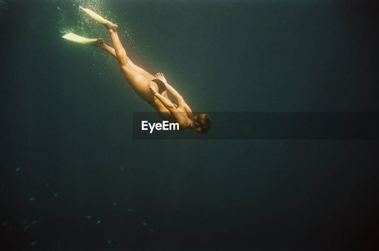 Woman free diving near nusa penida, bali, indonesia. nikonos v on 35mm cinestill 400d film.