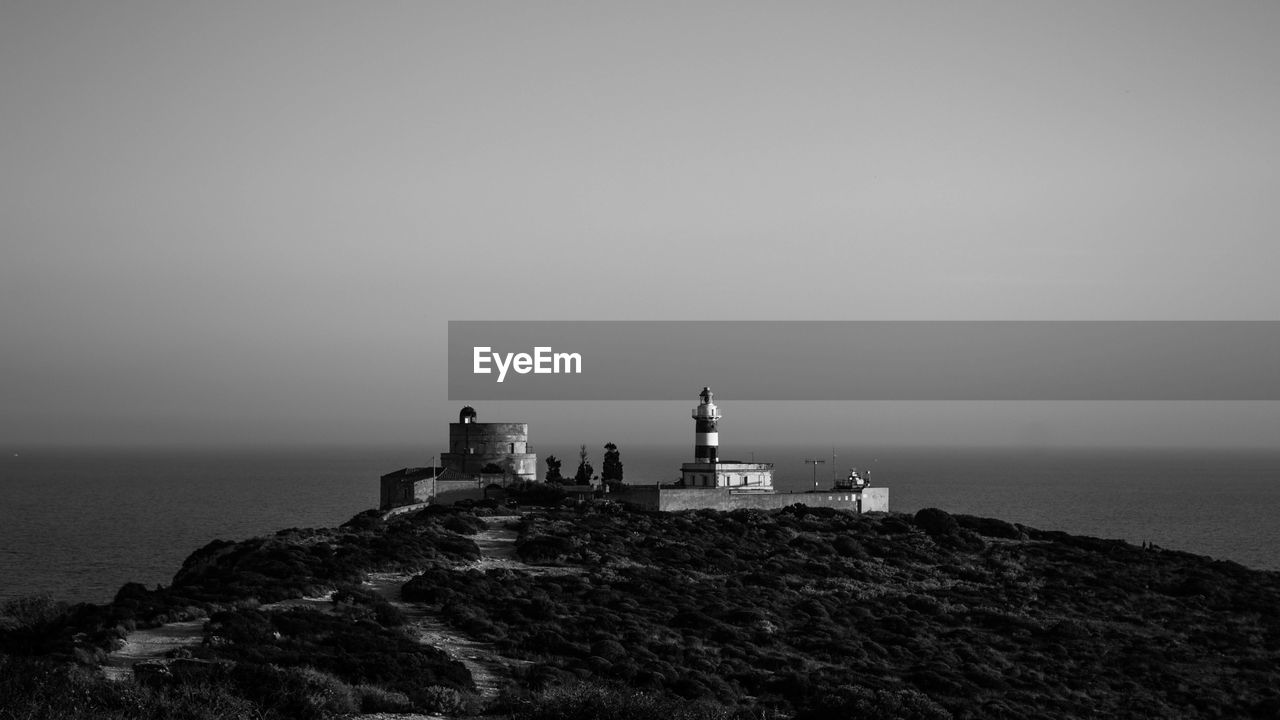 Lighthouse by sea against sky