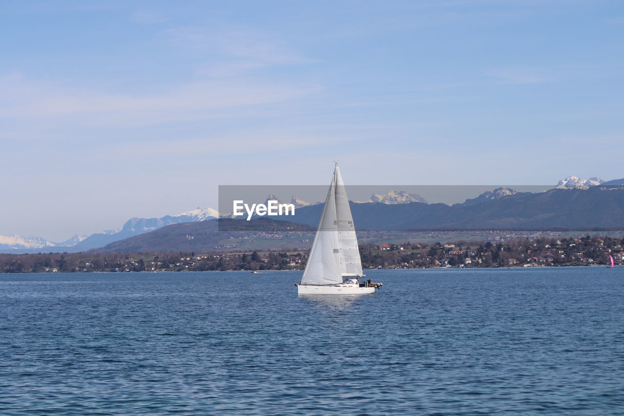 SAILBOAT SAILING ON SEA AGAINST MOUNTAIN