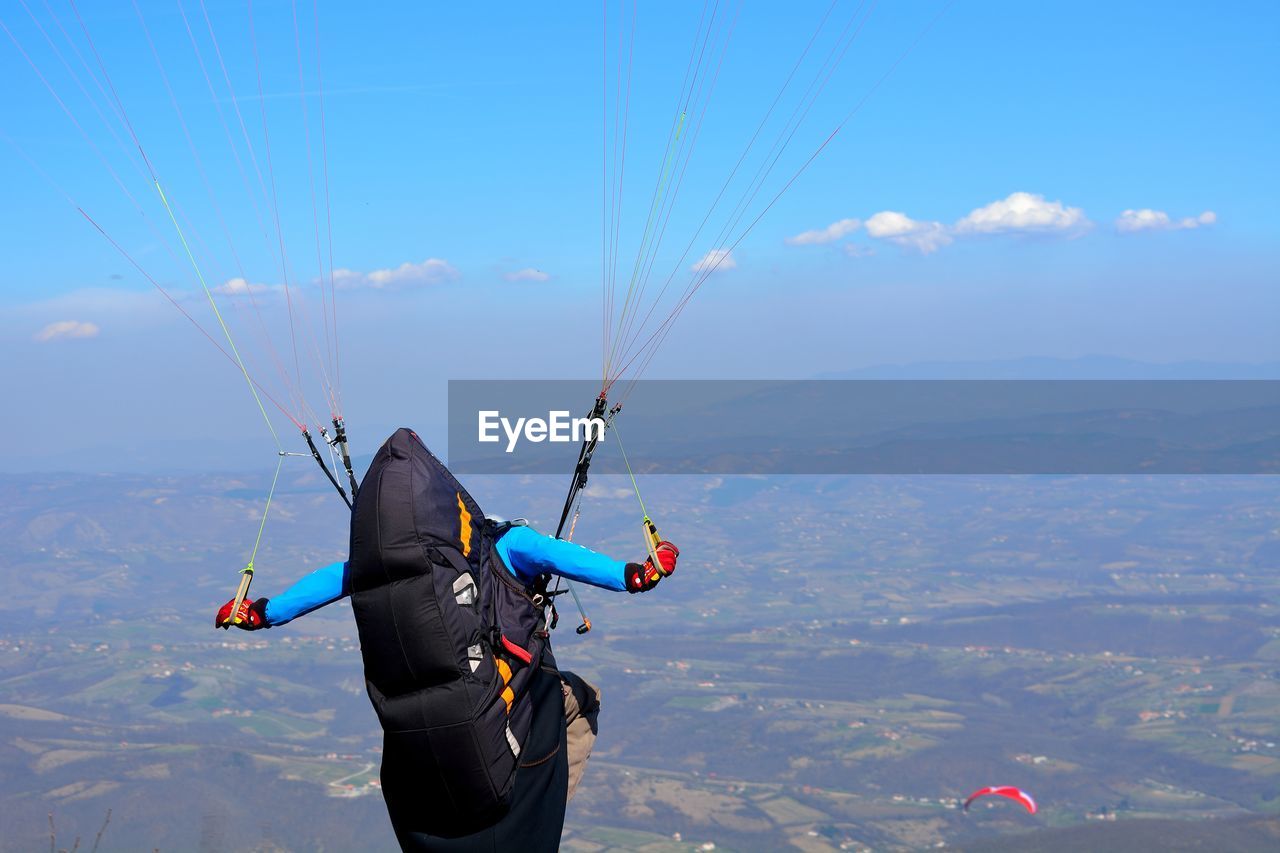 Low angle view of person paragliding over landscape