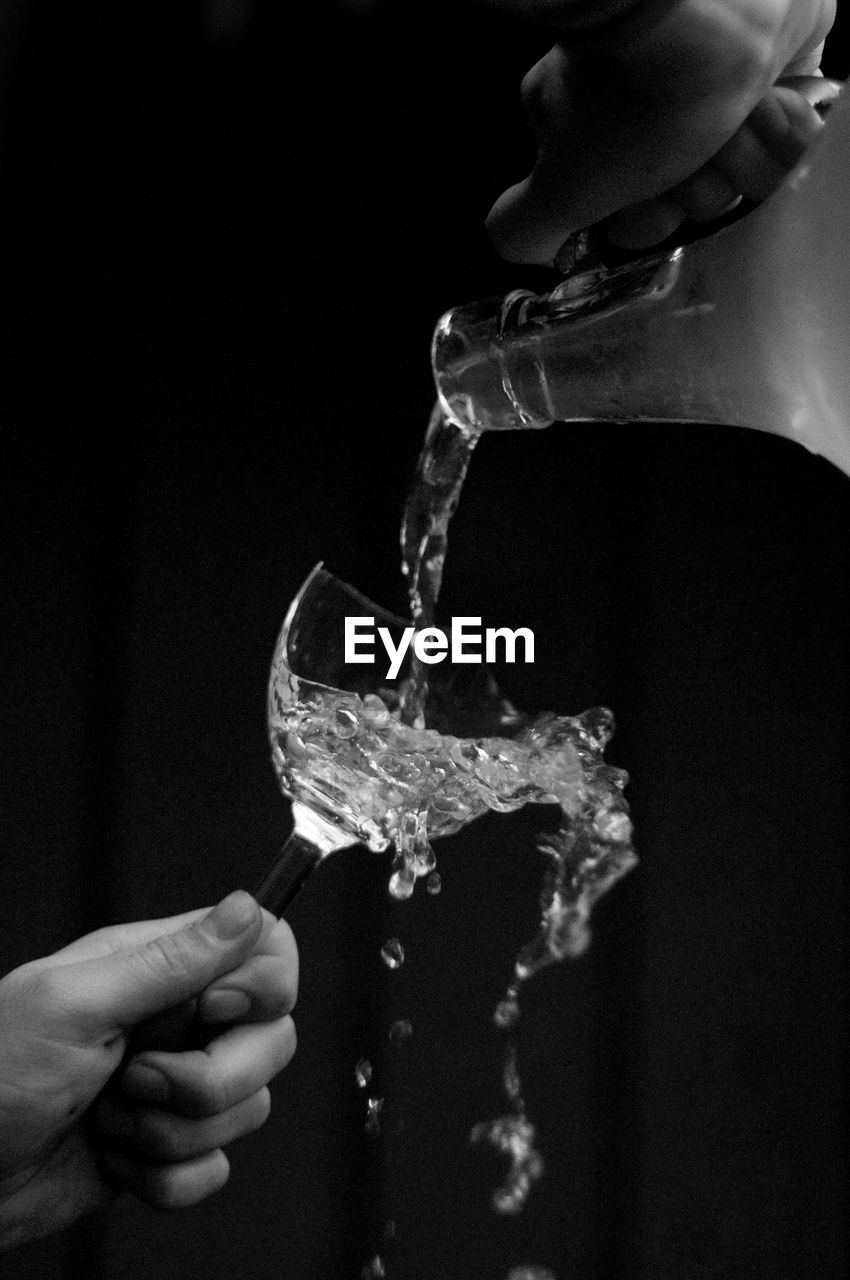 Close-up of hand splashing water against black background
