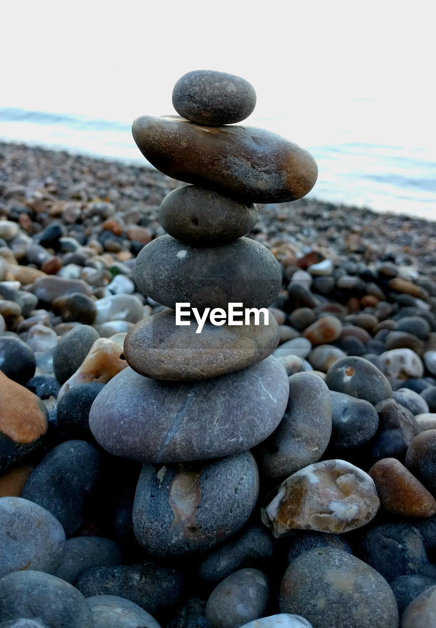 Stack of pebbles on beach against sky