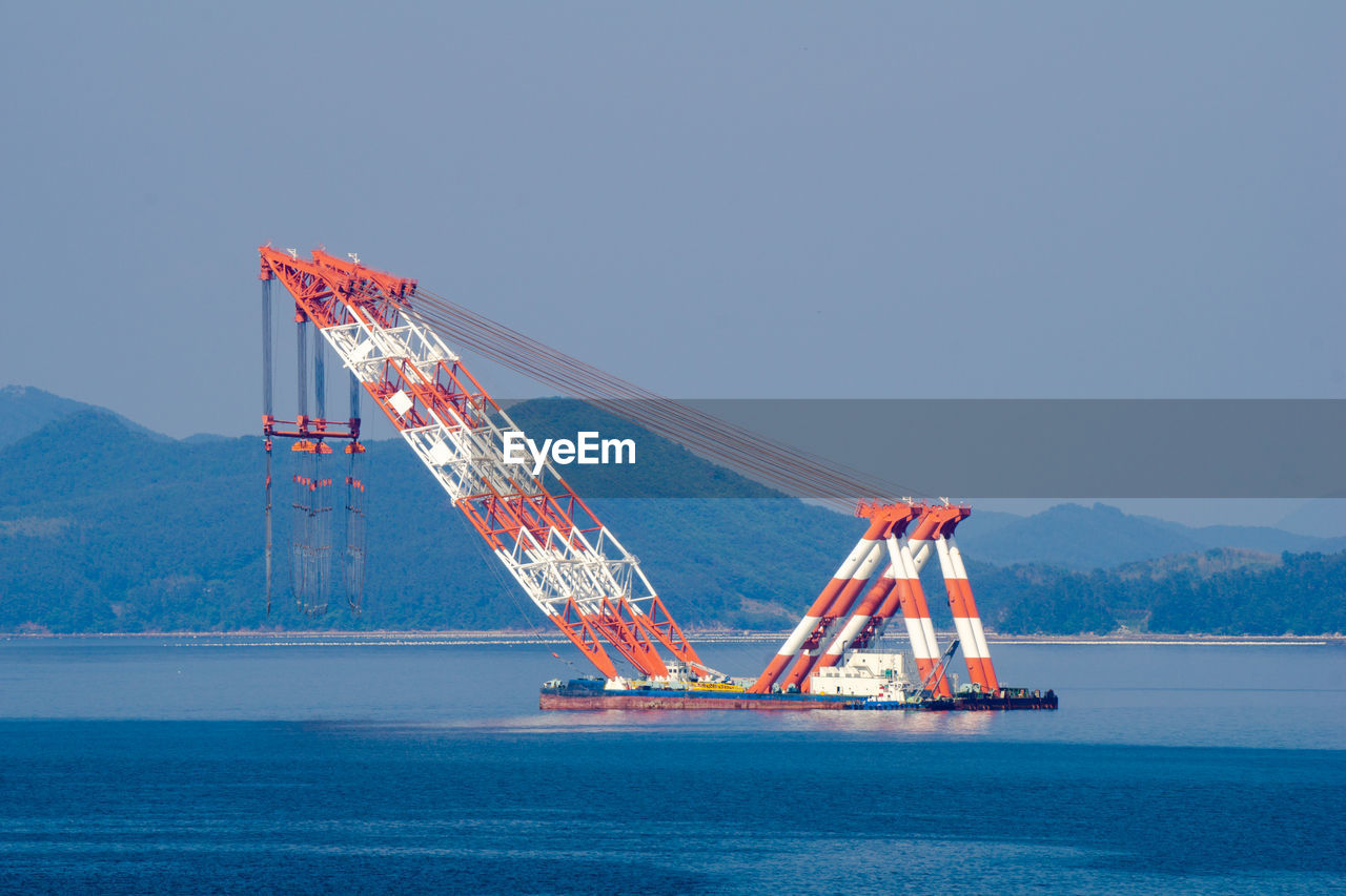 VIEW OF CRANE AGAINST SEA