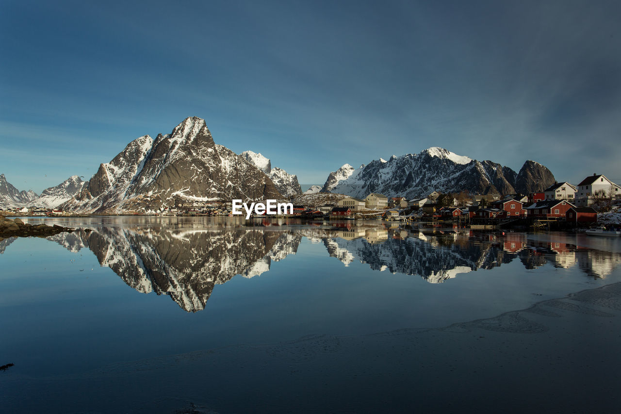 Scenic view of lake by snowcapped mountains against sky