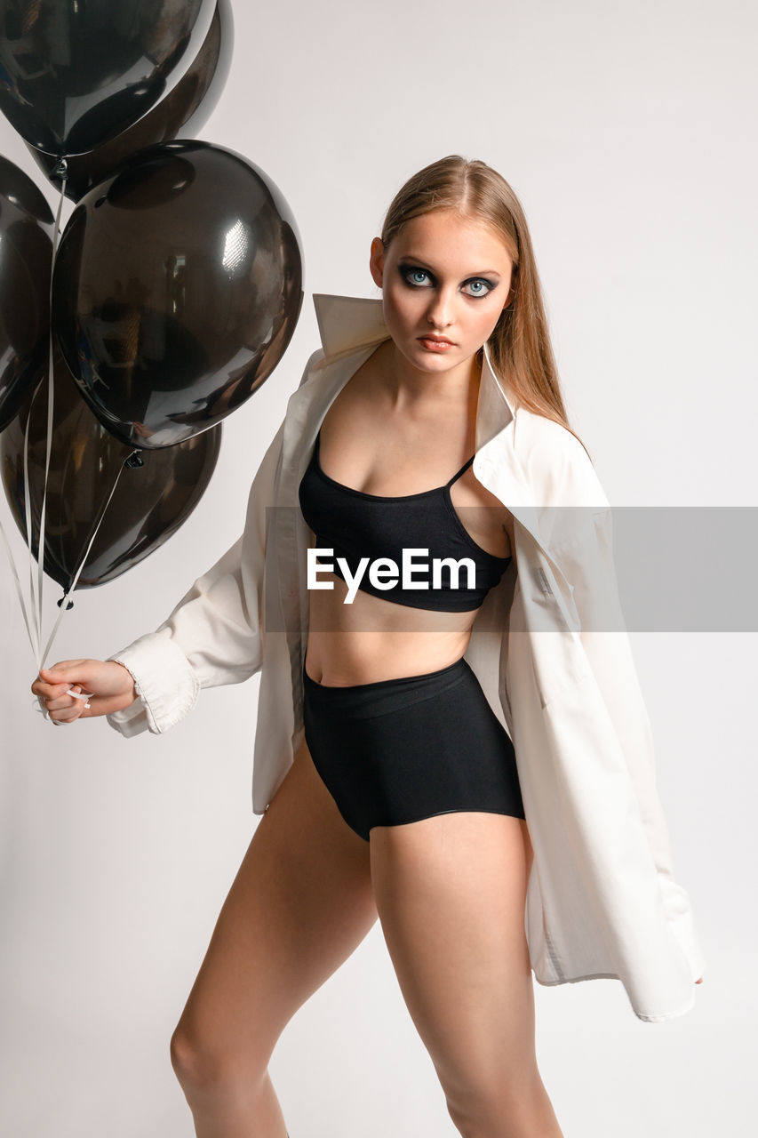 Teen girl model in sports underwear  posing in the studio on a white background with balloons