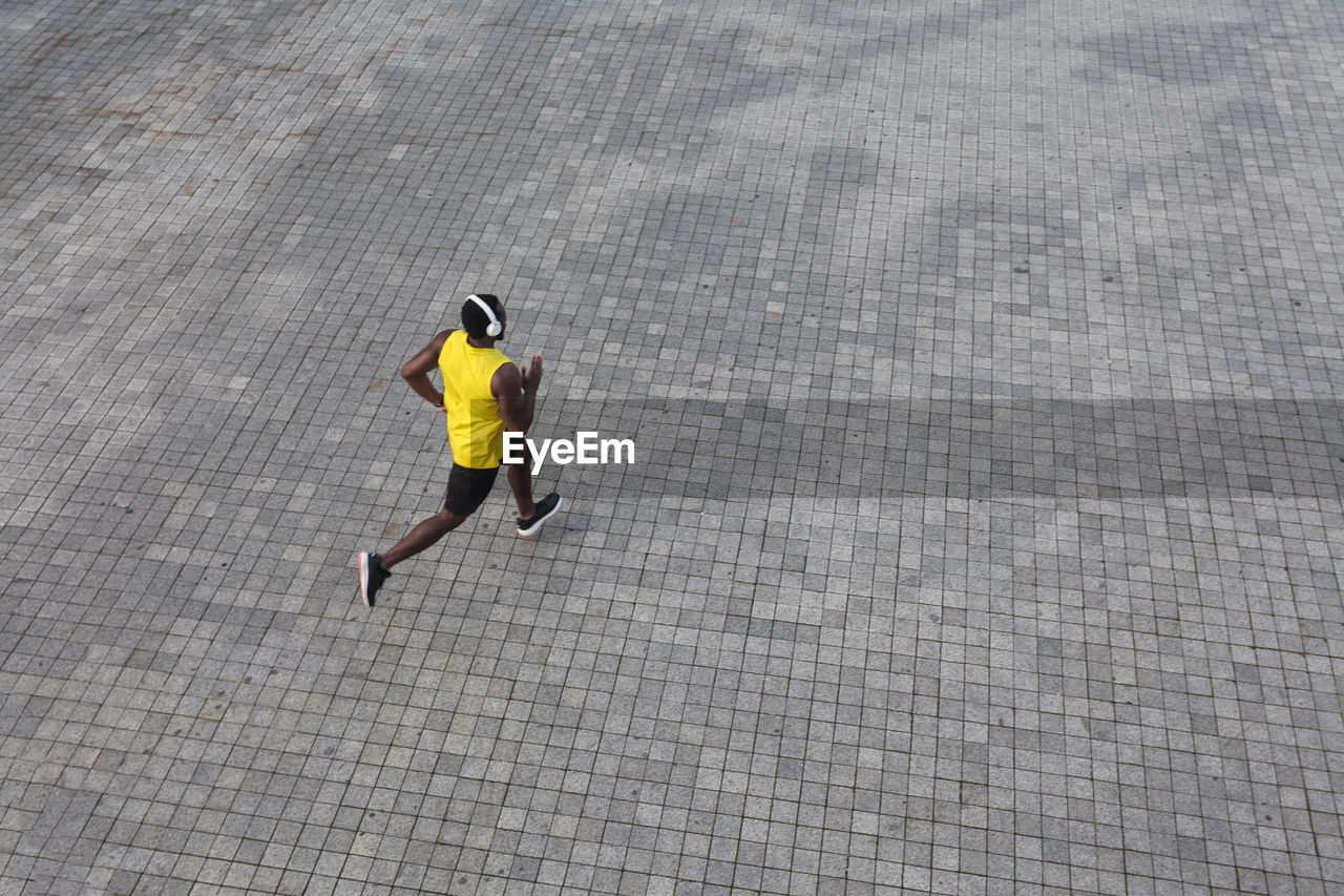 HIGH ANGLE VIEW OF MAN WALKING ON FOOTPATH