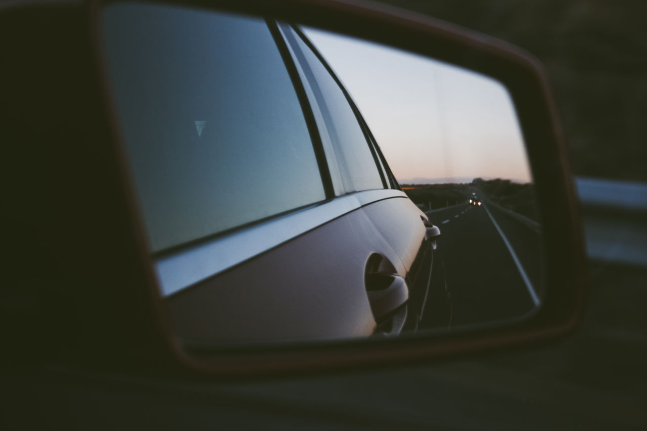 Road reflecting on side-view mirror of car