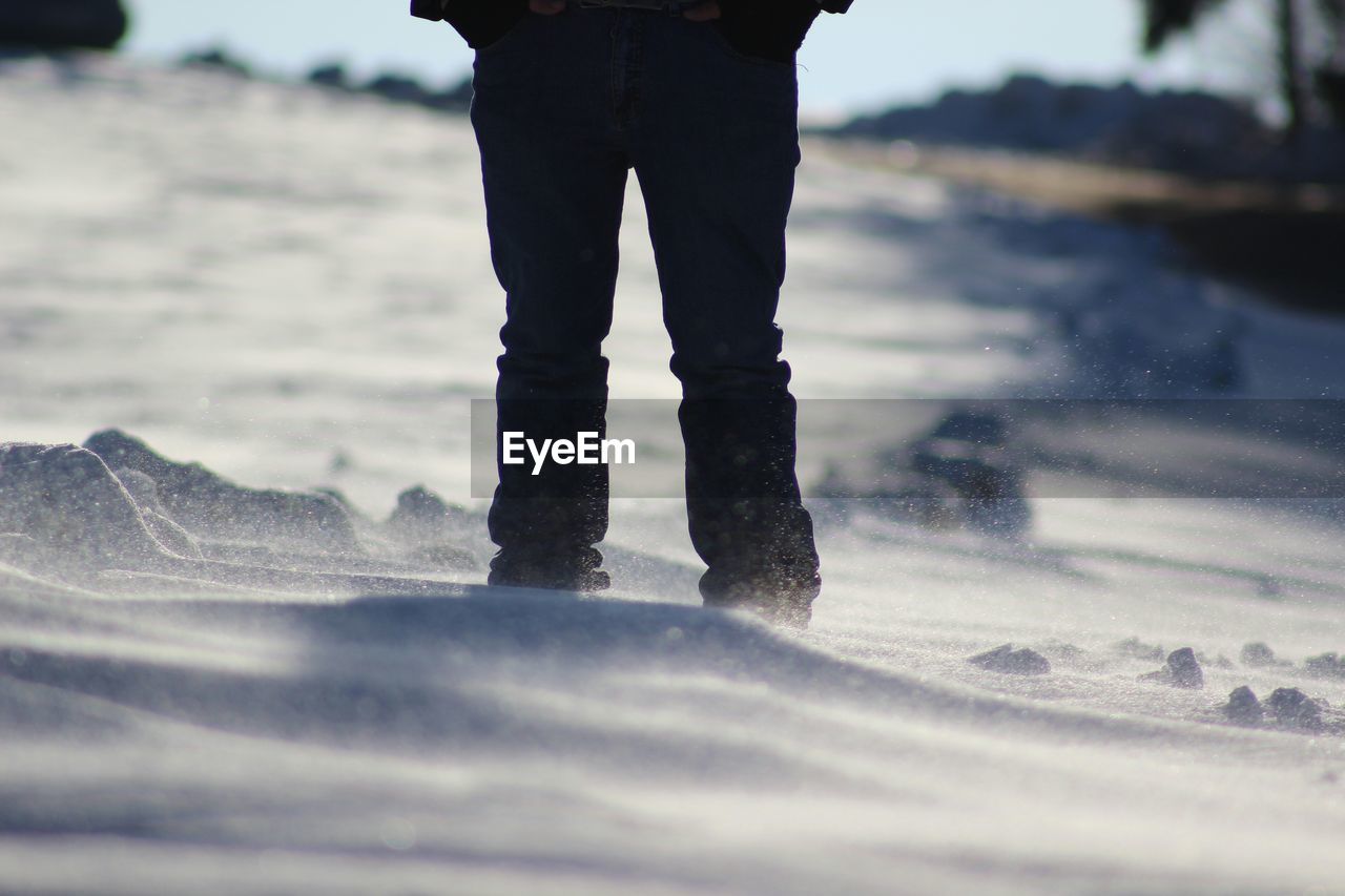 Low section of man standing on snow covered field