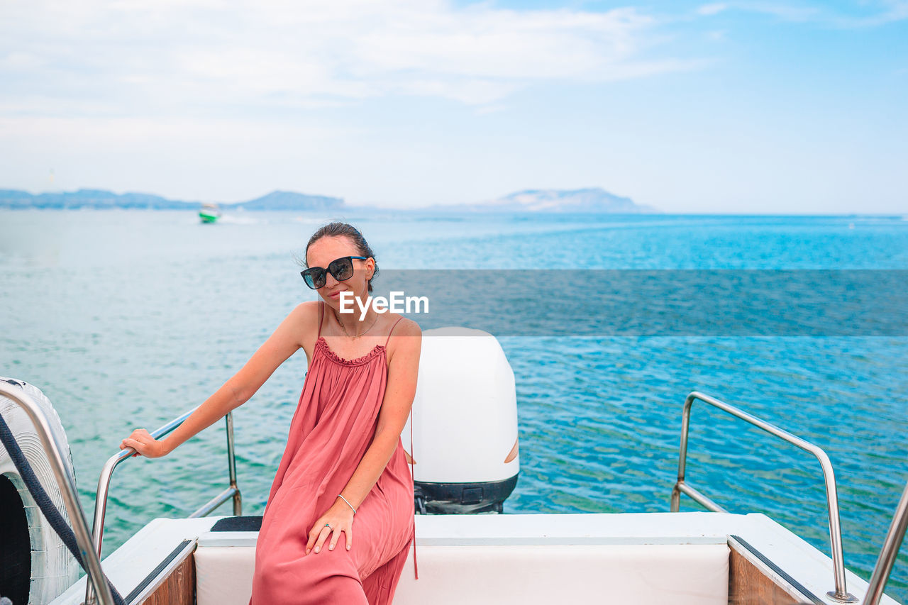 MAN WEARING SUNGLASSES ON BOAT AGAINST SEA