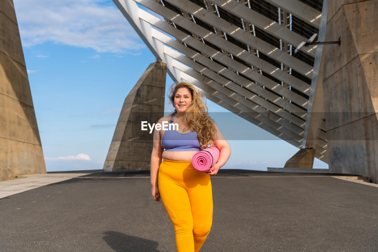 Portrait of young woman walking against building