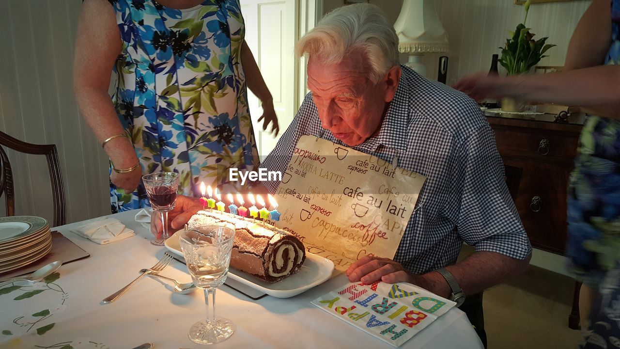 Senior man looking at illuminated birthday candles in living room