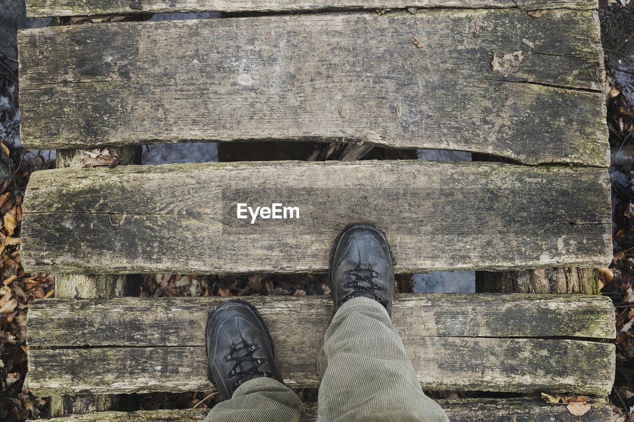 Low section of man standing on boardwalk