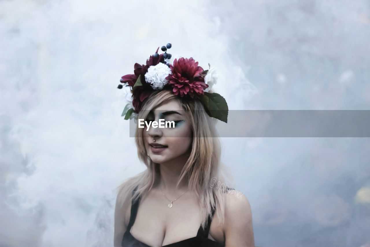 Close-up of beautiful woman wearing flowers while standing outdoors