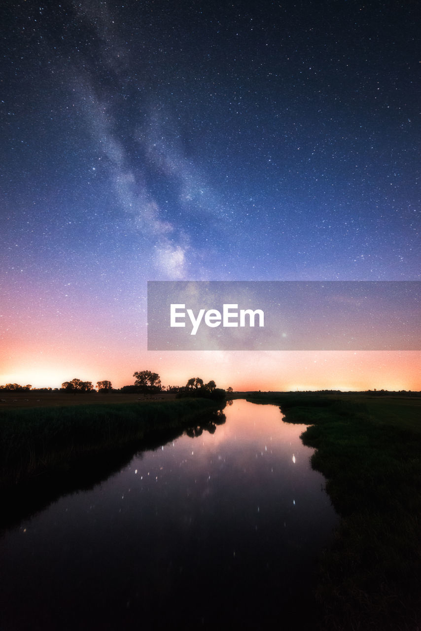 SCENIC VIEW OF LAKE AGAINST STAR FIELD IN SKY AT NIGHT