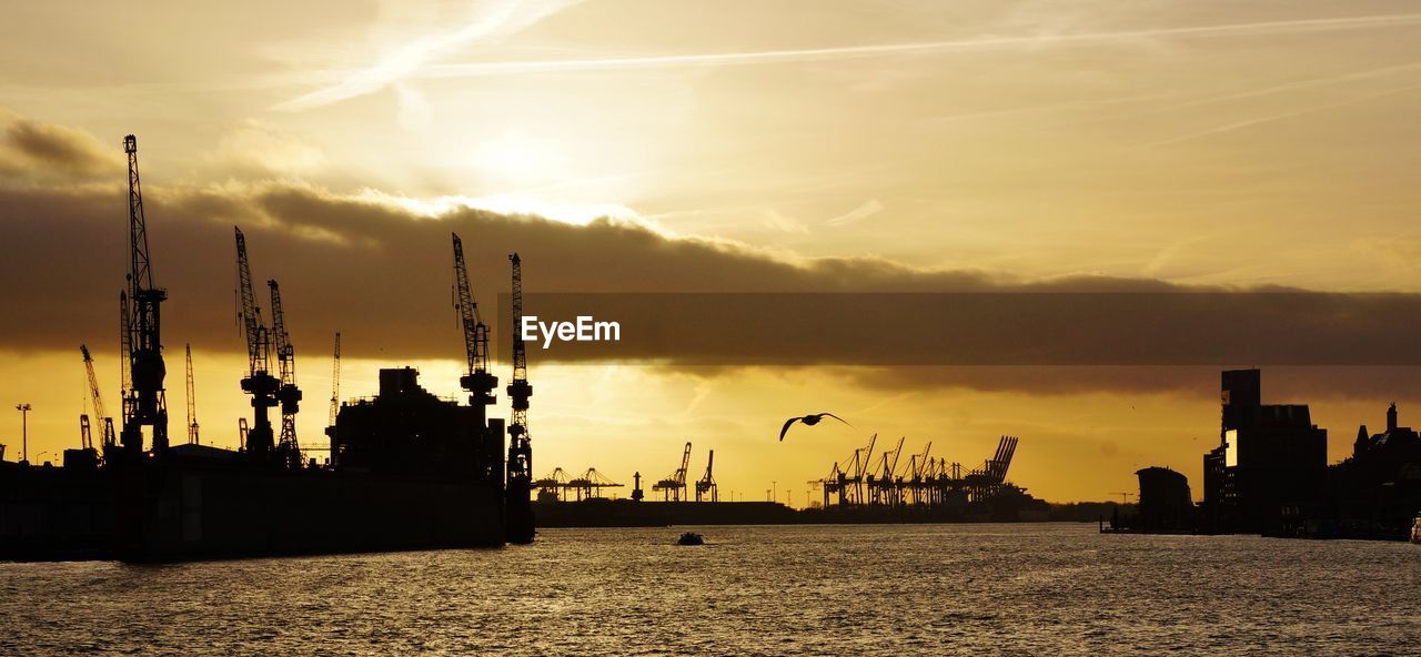 Silhouette cranes at port of hamburg during sunset