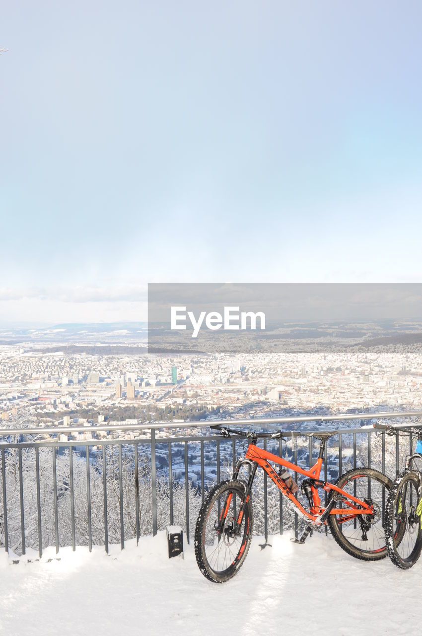 Bicycles parked on observation point during winter against sky