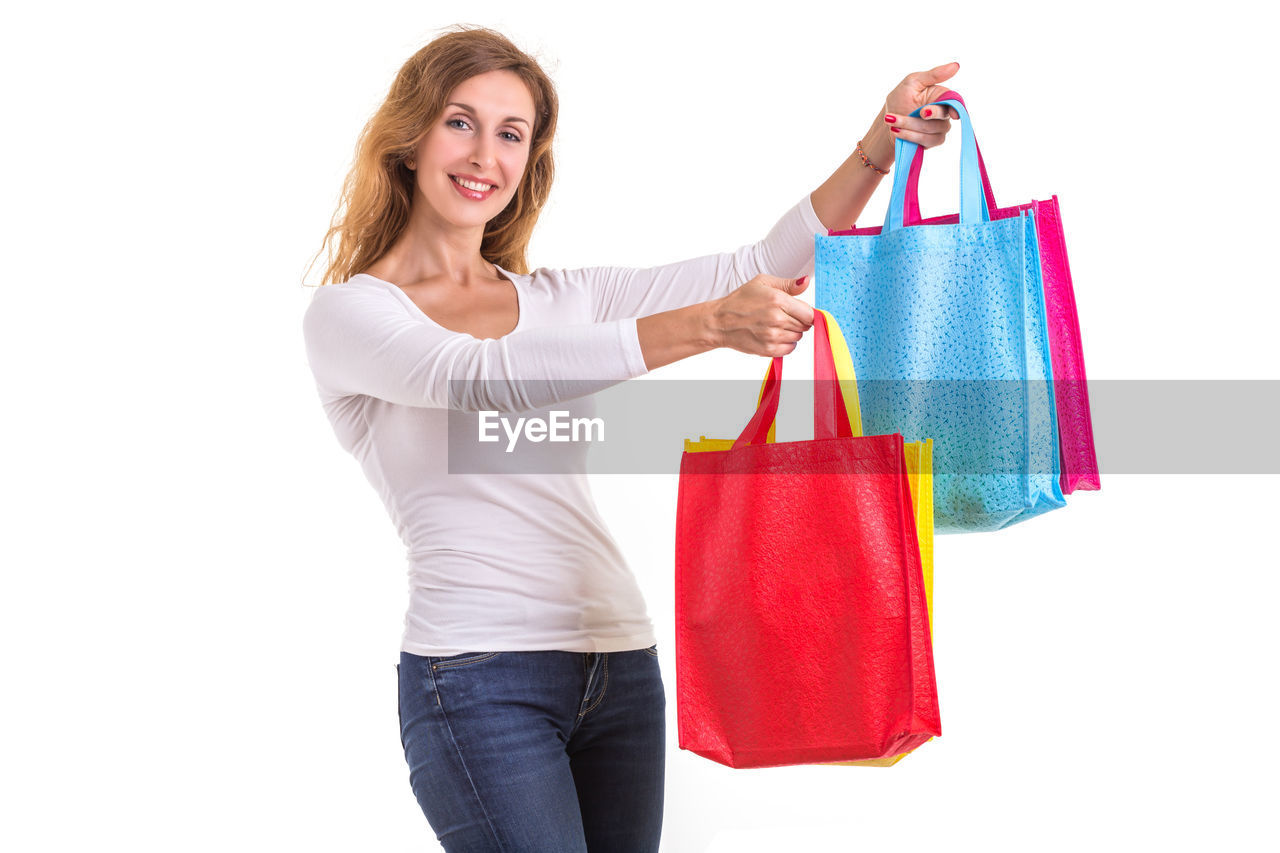 Portrait of woman holding shopping bags against white background