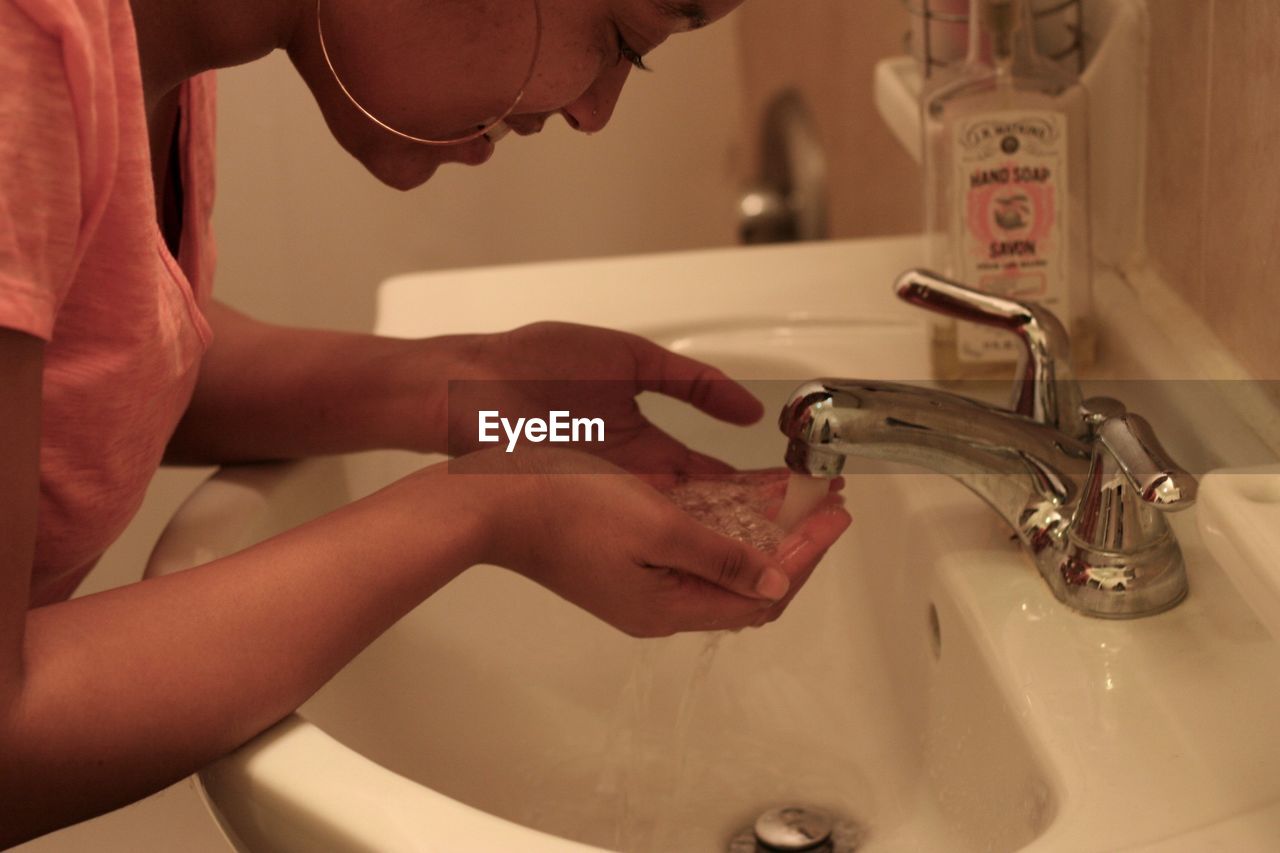 Midsection of woman washing face in bathroom