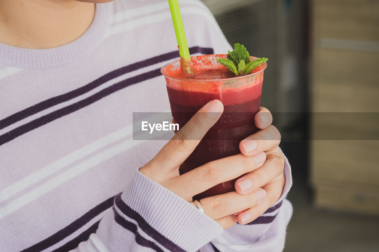 Midsection of woman holding beetroot smoothie