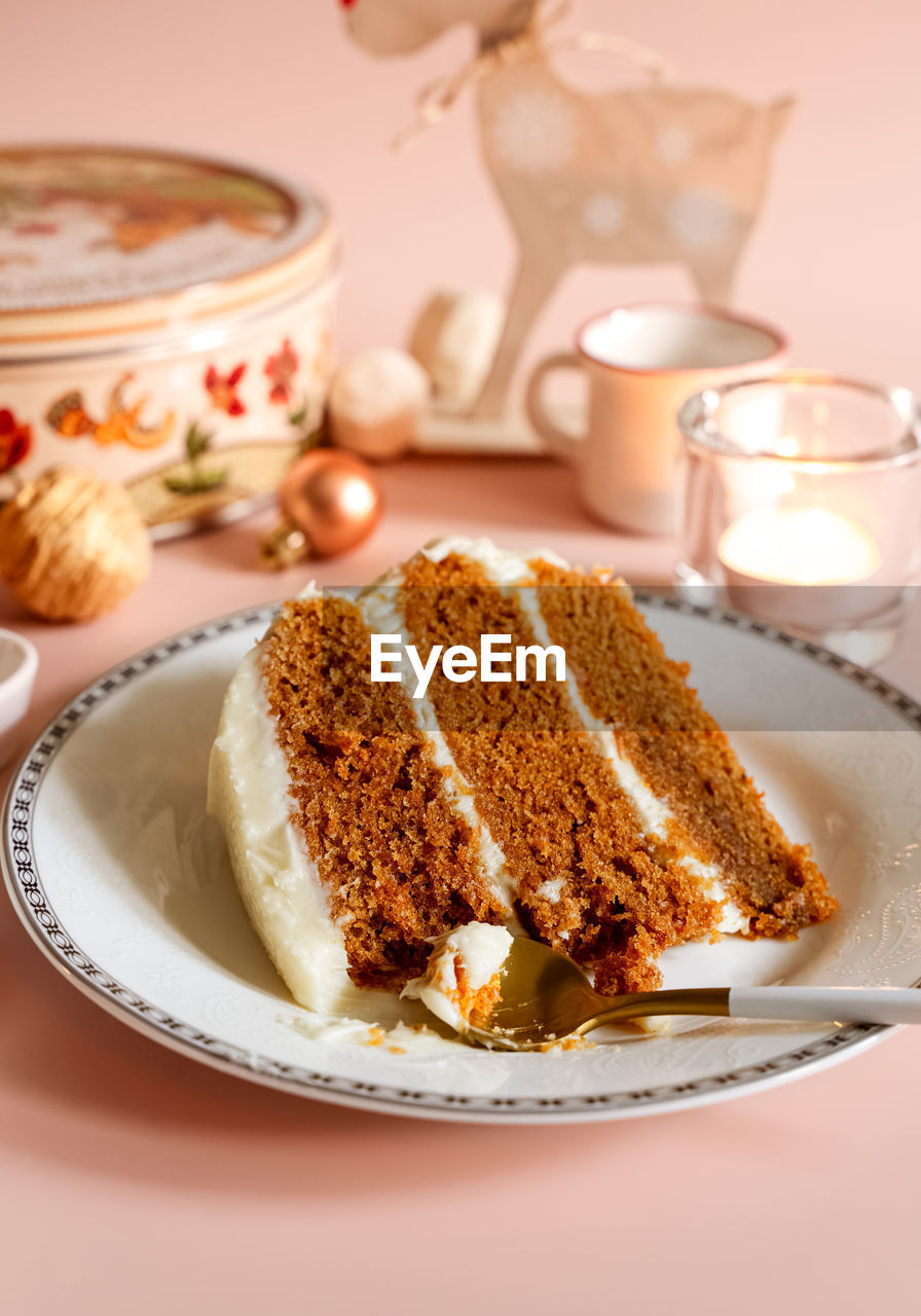 Piece of carrot layer cake, spoon on white plate with christmas seasonal background. 