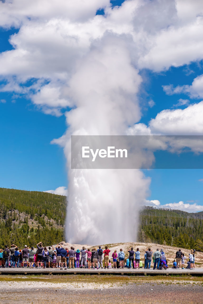 rear view of man standing by waterfall against sky