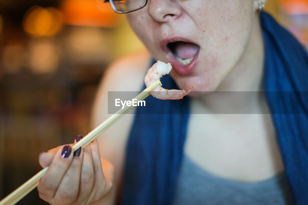 Close-up of woman eating prawn at home