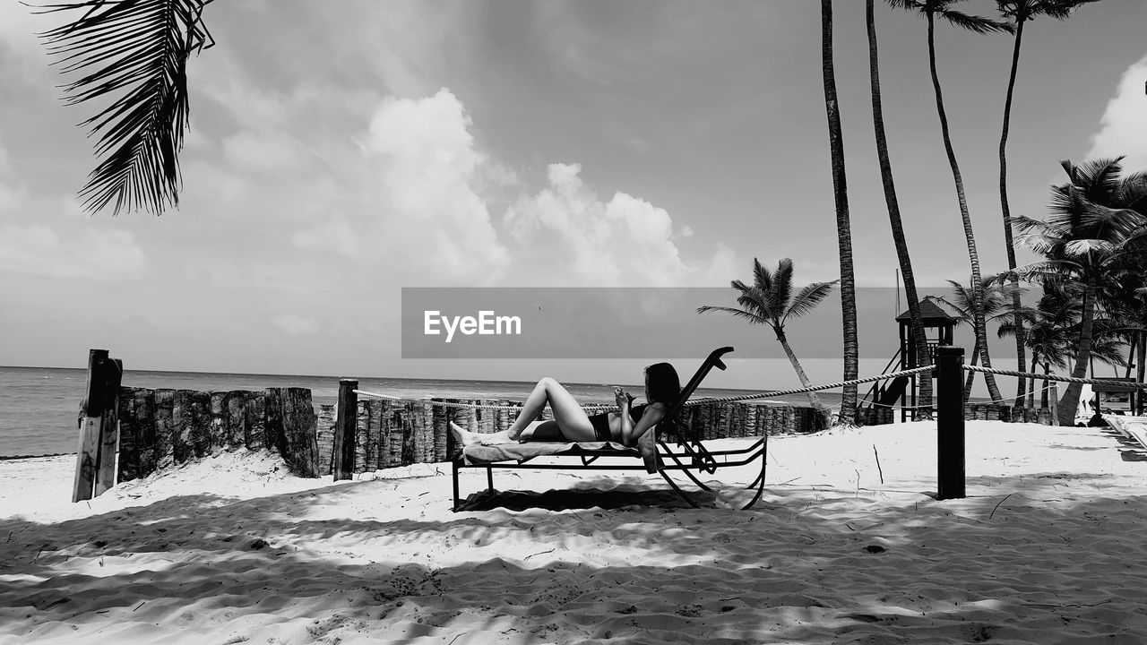 Woman relaxing on lounge chair at beach