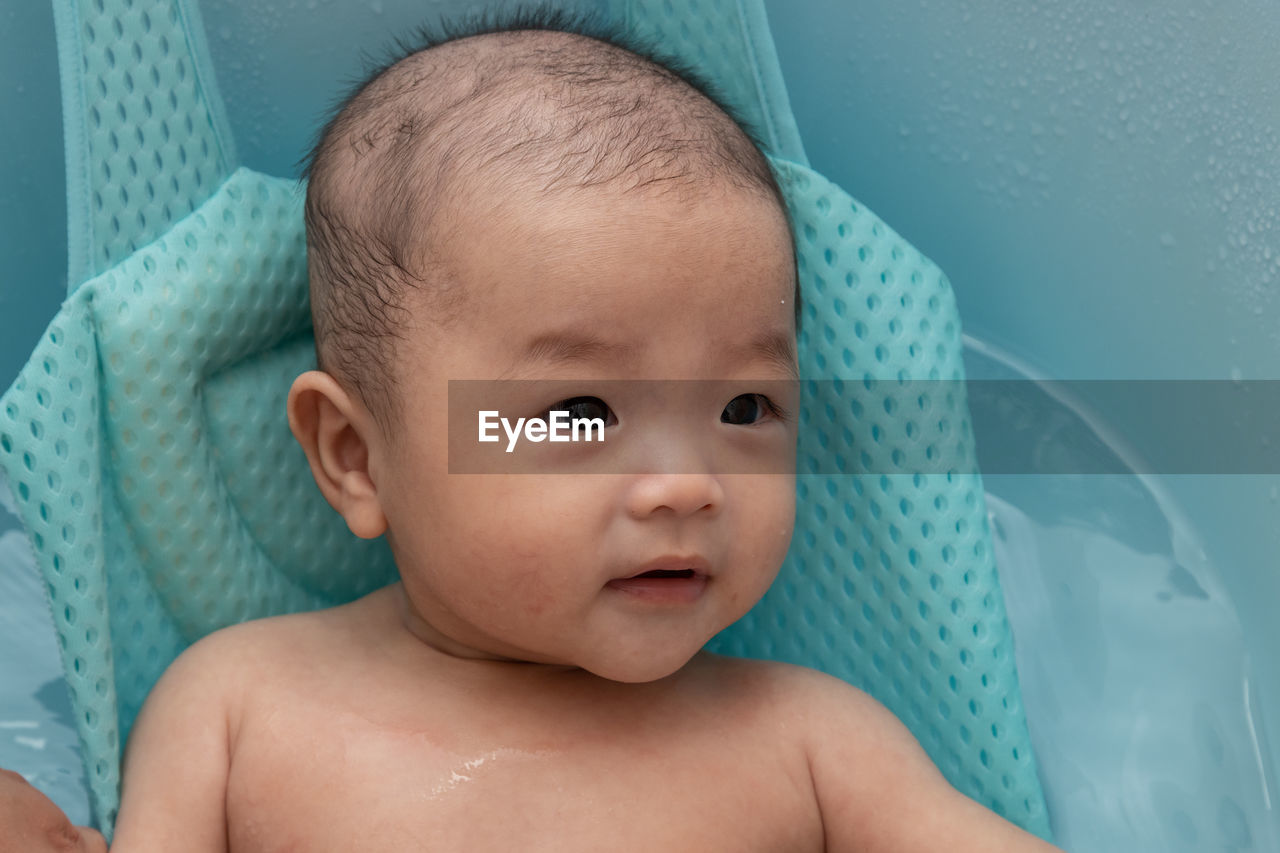 Cute baby girl lying in container