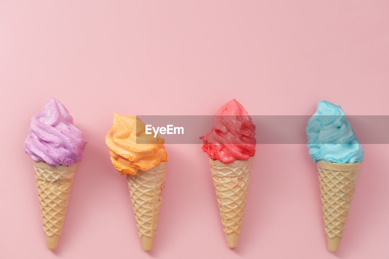 LOW ANGLE VIEW OF ICE CREAM CONE AGAINST PINK BACKGROUND