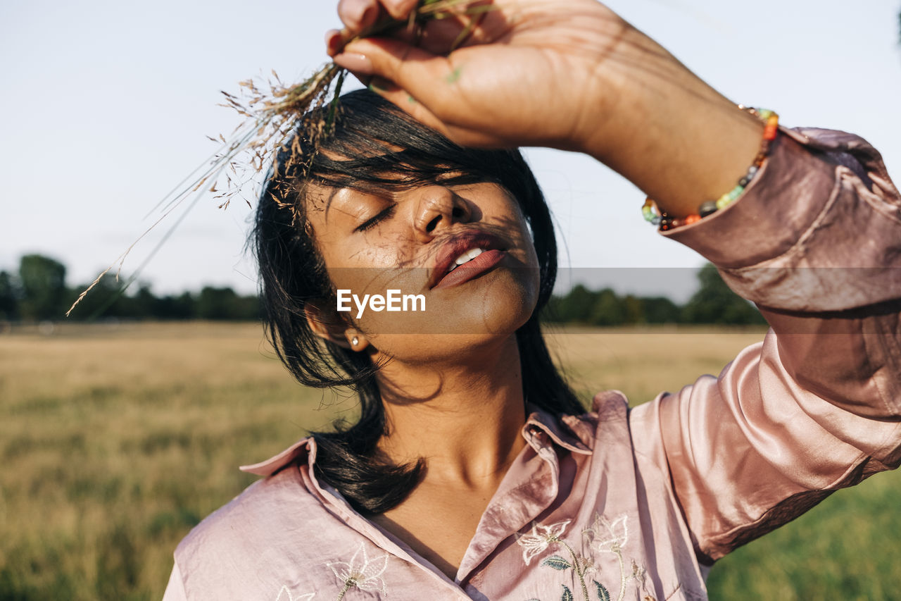 Woman with eyes closed holding grass at park