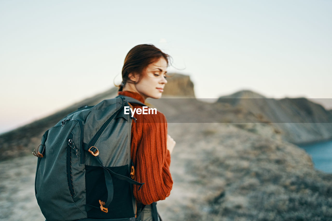 BEAUTIFUL YOUNG WOMAN STANDING AGAINST SKY