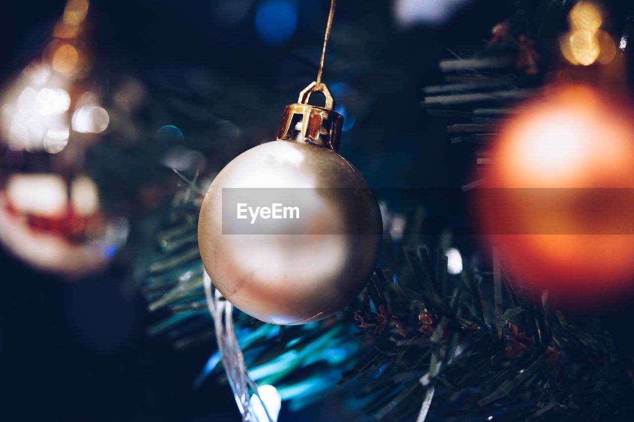 Close-up of baubles on illuminated christmas tree at night