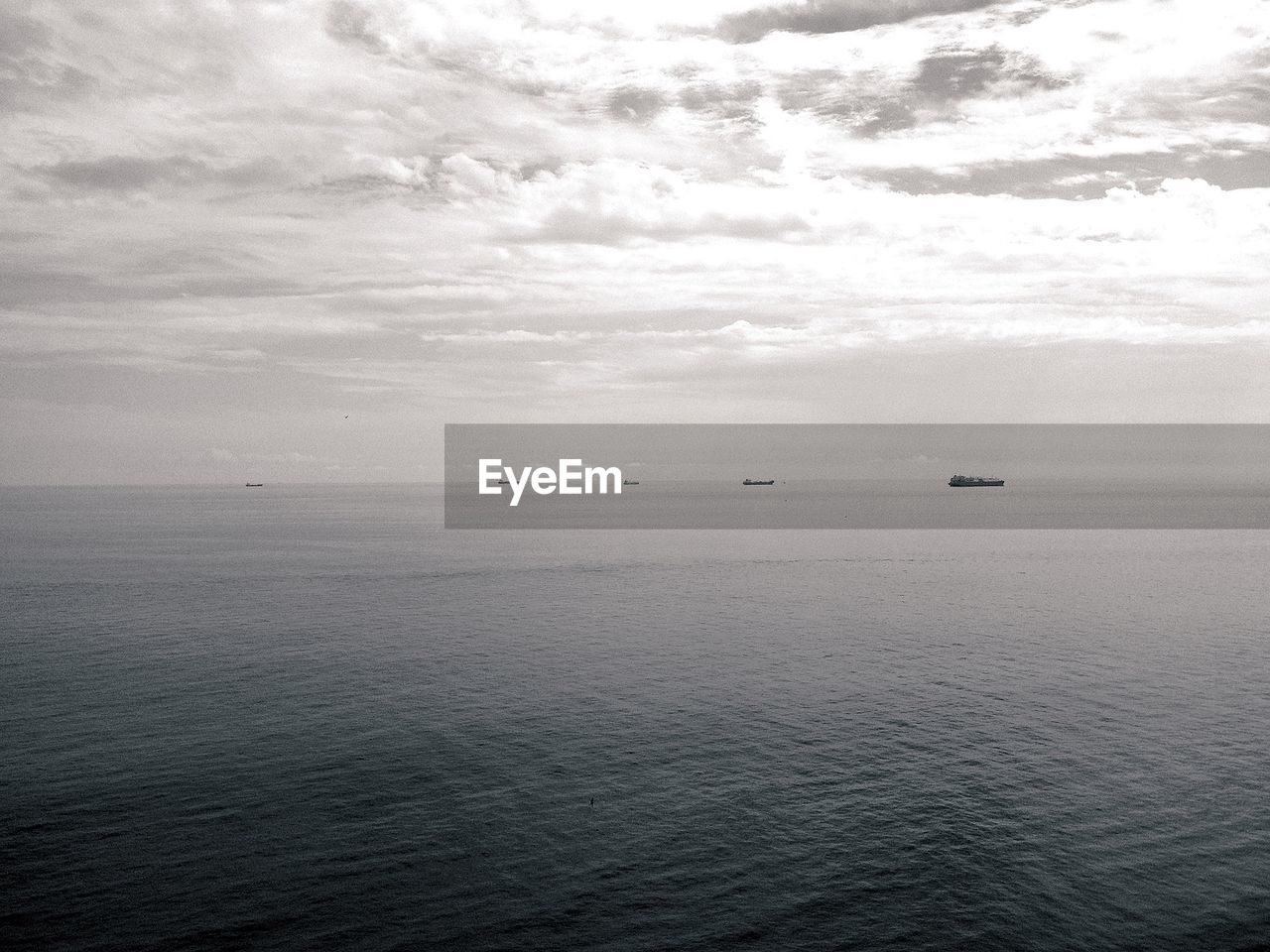 Boats sailing on sea against cloudy sky