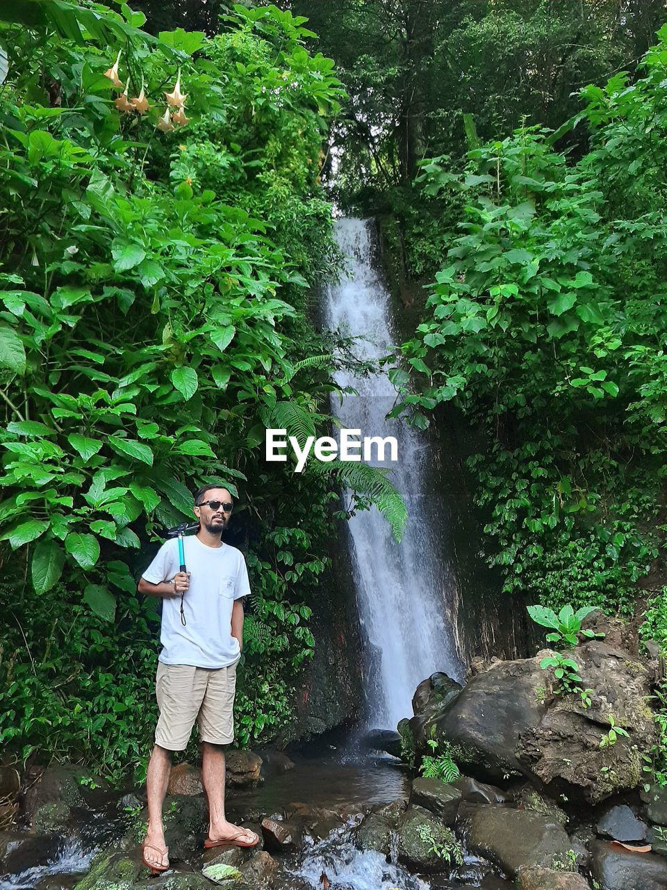 MAN STANDING BY WATERFALL