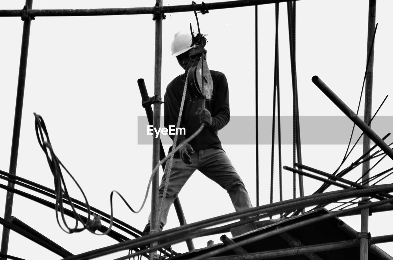 Low angle view of worker working at construction site against sky