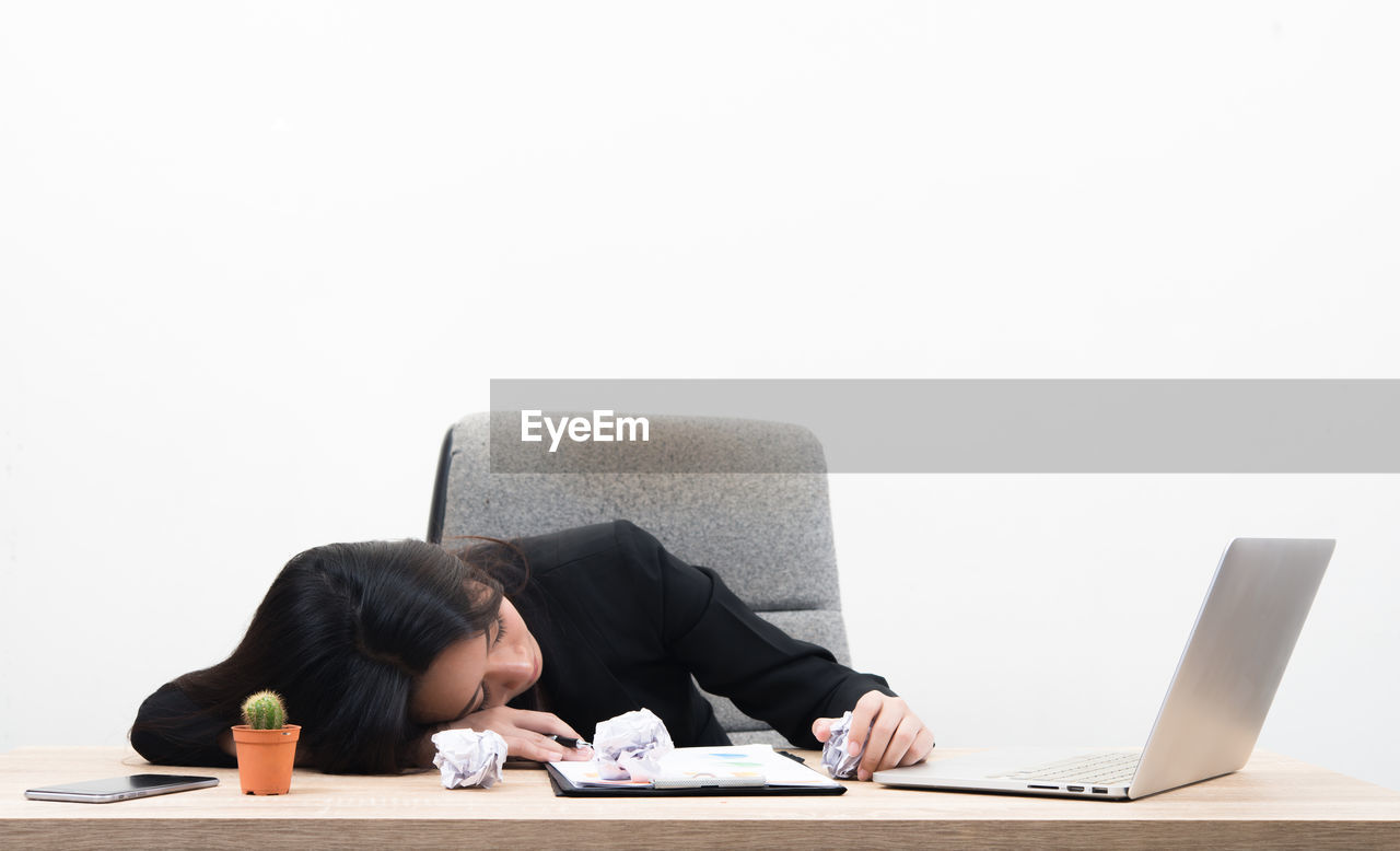 Young businesswoman napping by laptop on table