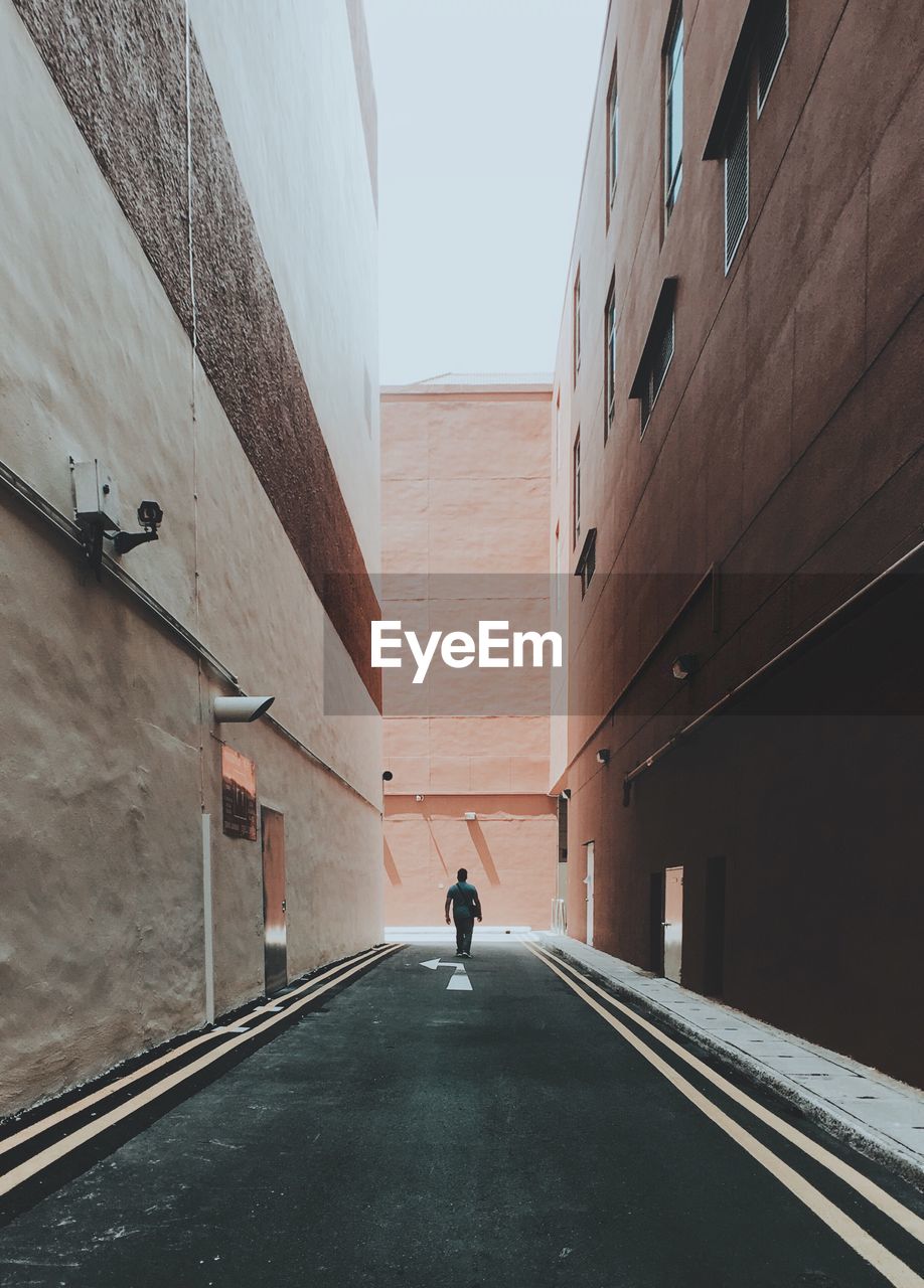 Man walking on road amidst buildings