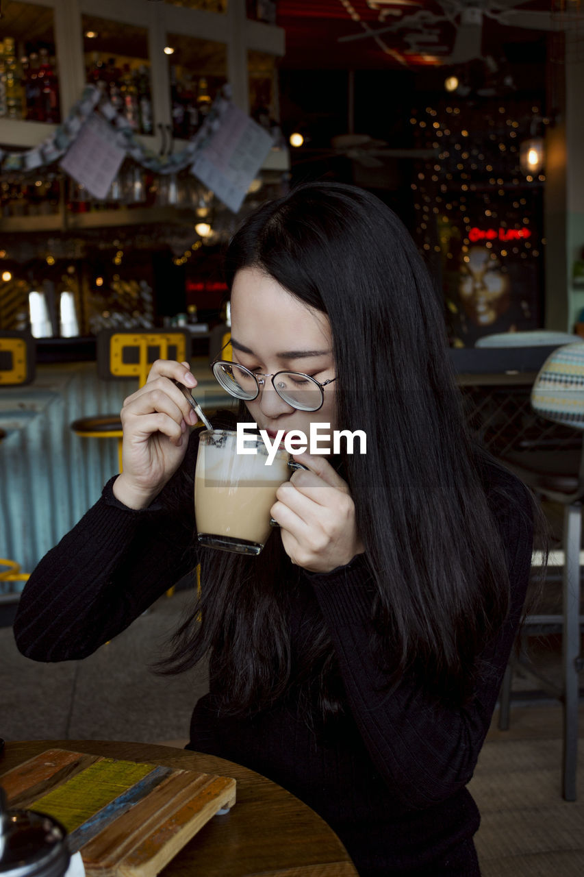 Young woman drinking coffee at sidewalk cafe