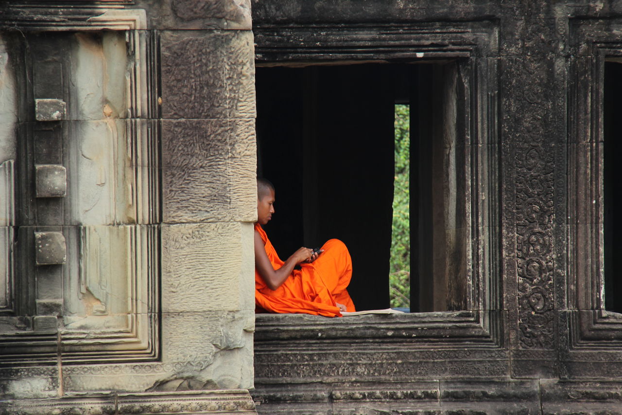 LOW ANGLE VIEW OF MAN AT TEMPLE AGAINST BUILDING