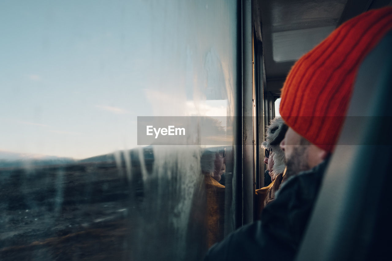 REFLECTION OF MAN ON TRAIN WINDOW AT RAILROAD TRACK