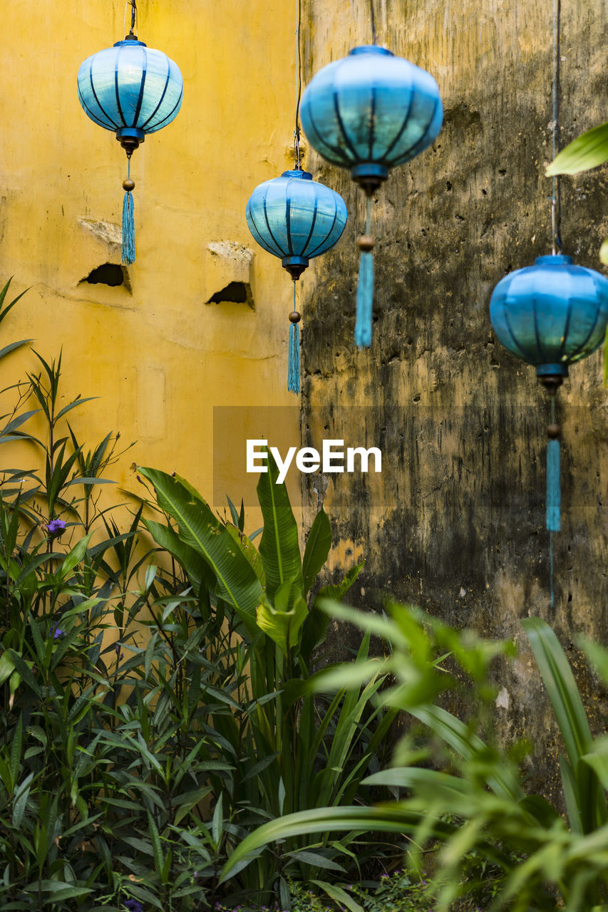 Latern out of silk  hanging in front of a yellow wall 