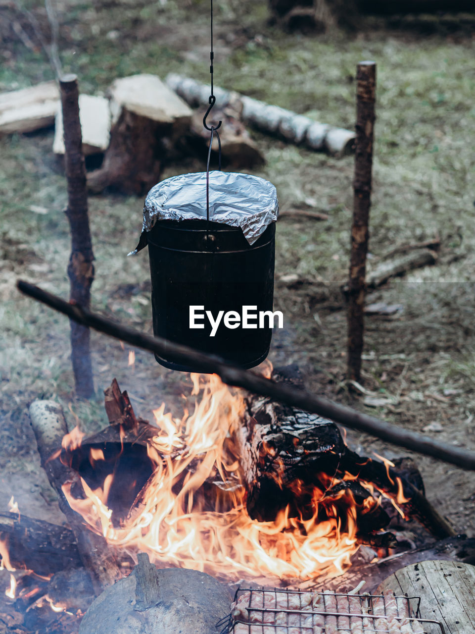 The kettle hangs over the fire. cooking at the campsite. camping detail, travel lifestyle photo.