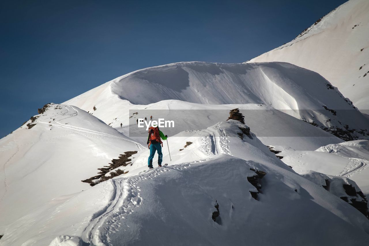 Low angle view of hiker hiking on snowcapped mountain