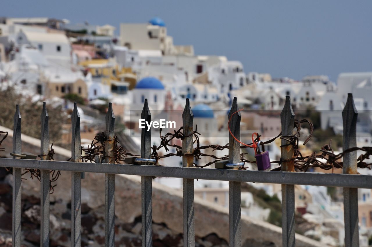 Close-up of padlocks on fence against houses at santorini