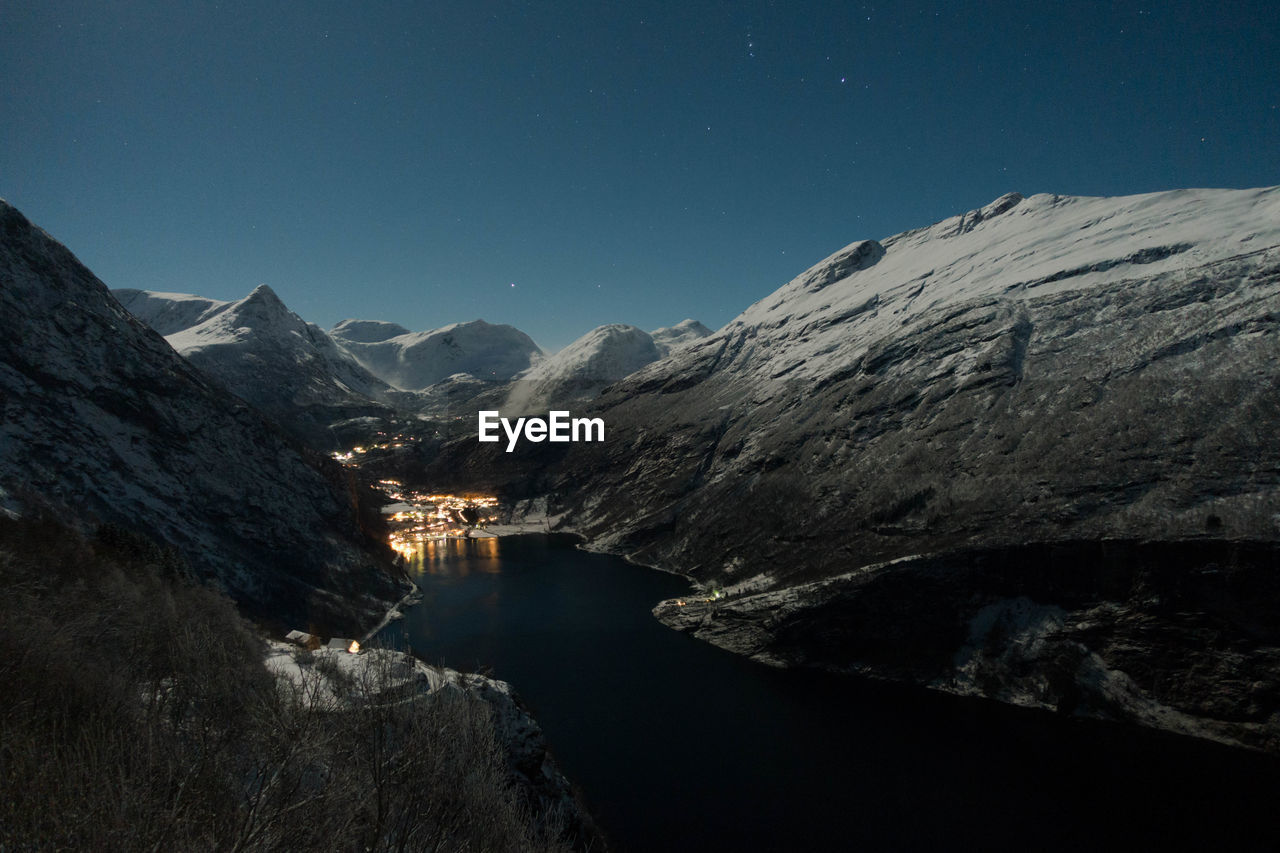 Scenic view of river amidst mountains against clear blue sky