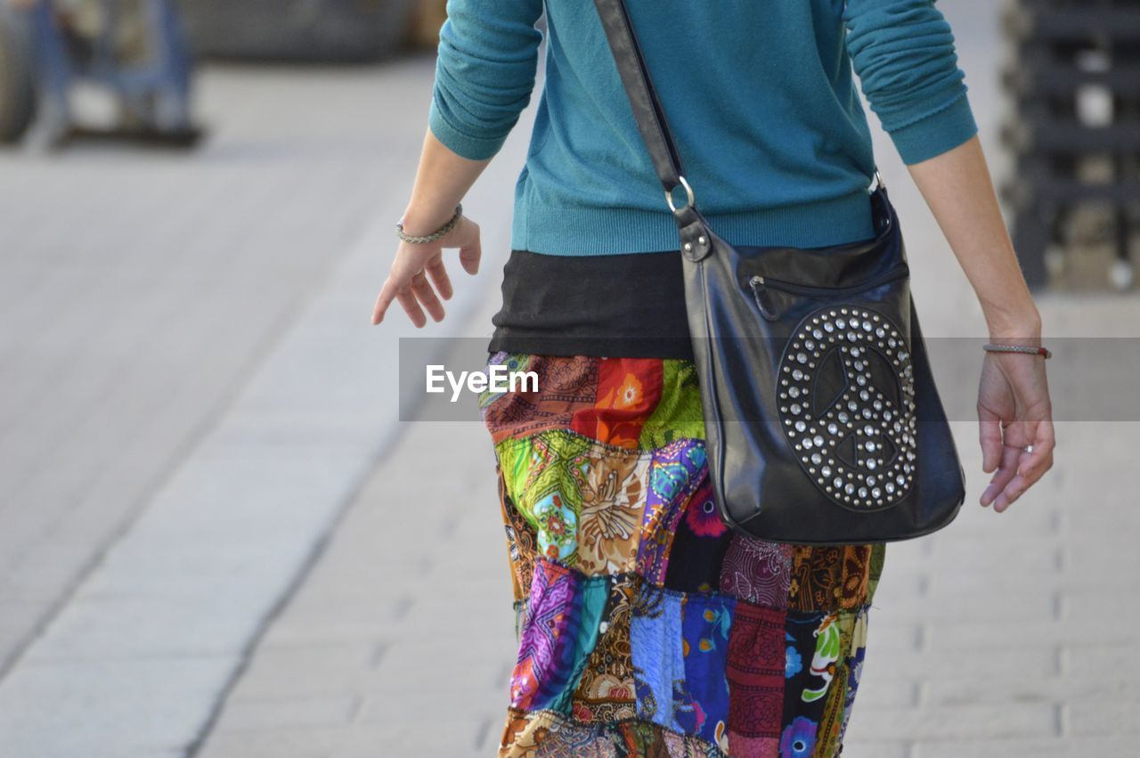Midsection of woman with purse walking on footpath