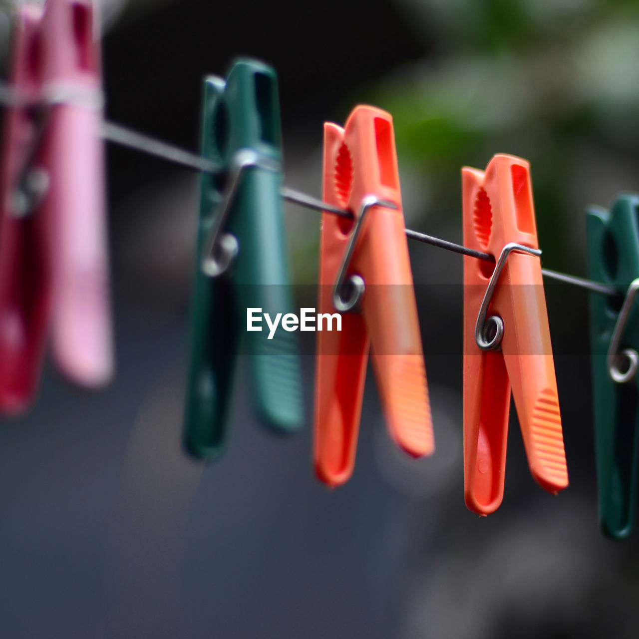 CLOSE-UP OF MULTI COLORED CLOTHESPINS HANGING ON ROPE