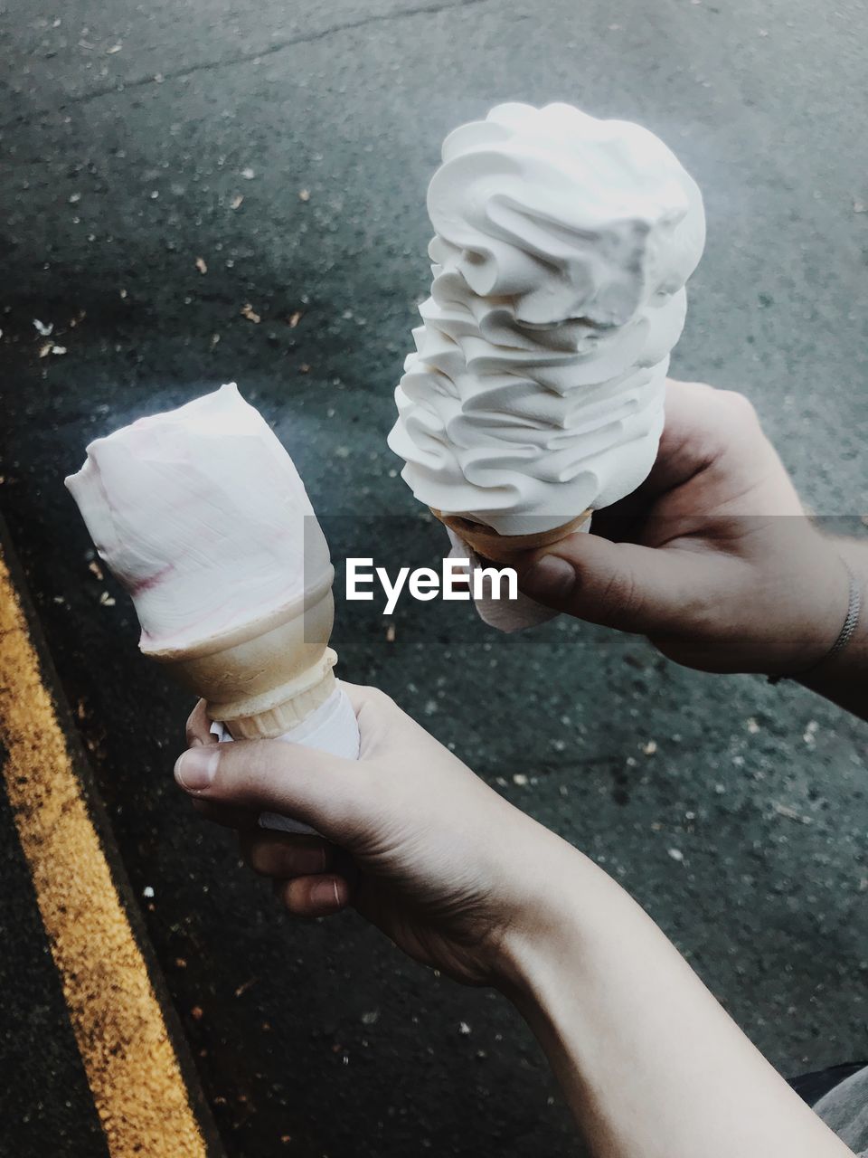 Cropped image of hands holding ice creams on street