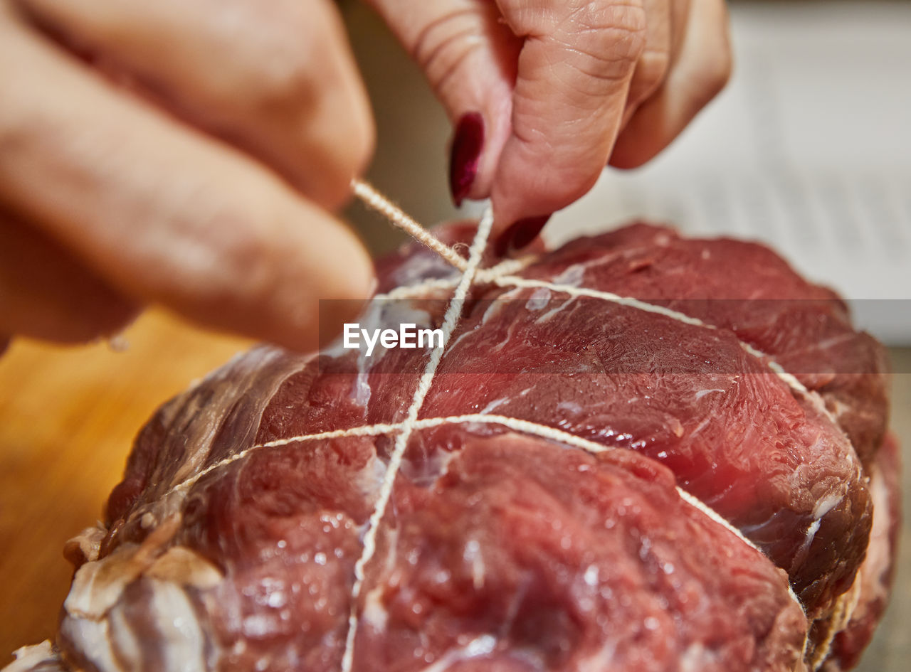 Chef ties the beef with rope and prepares it for baking in the oven